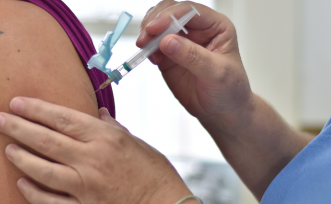 Enfermeira aplicando vacina no braço de uma mulher