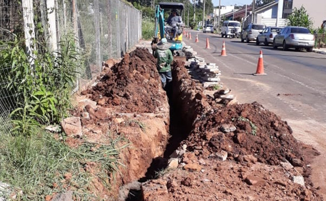 Em uma rua, homem trabalha dentro de um buraco colocando a canalização