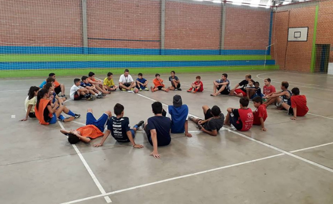 Em um quadra, jovens sentados em formato de círculo