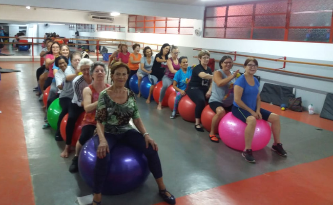 Em duas filas, mulheres sentadas em cima de bolas