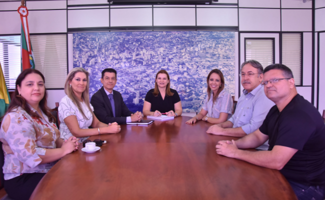 Sete pessoas sentadas no entorno de um mesa