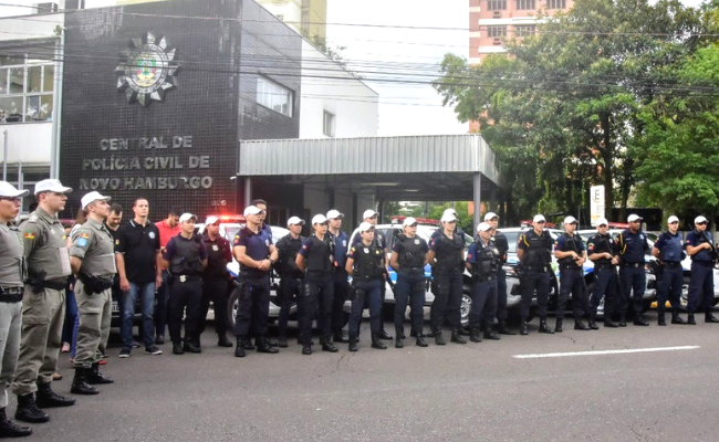 Em frente à Delegacia de Polícia, homens da Brigada Militar e Guarda Municipal perfilados lado a lado formando um "L"