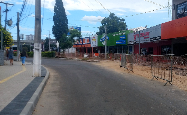 Rua asfaltada com lojas no lado esquerda 