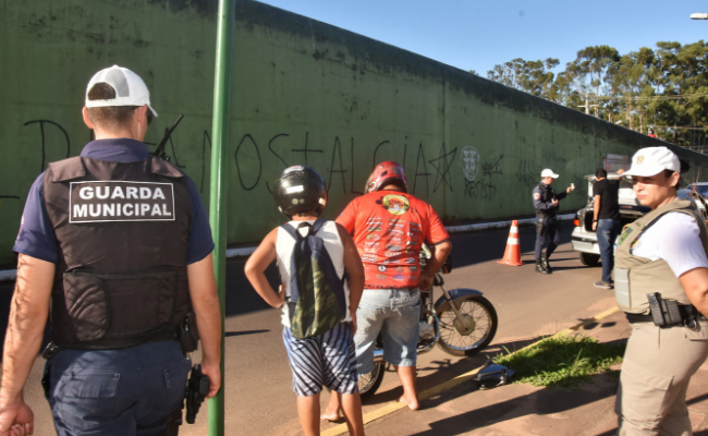 Em uma rua, agentes da Guarda Municipal e Brigada Militar param veículos e fazem uma revista