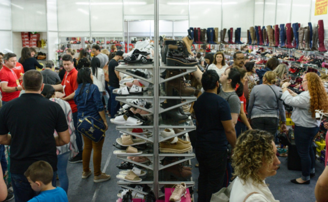 Pessoas olhando sapatos em estandes na Feira