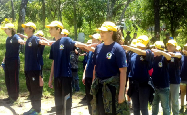 Em quatro filas, alunos vestindo azul marinho 