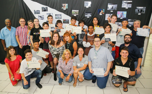 Formandos com o diploma na mão, uns em pé e outros agachados