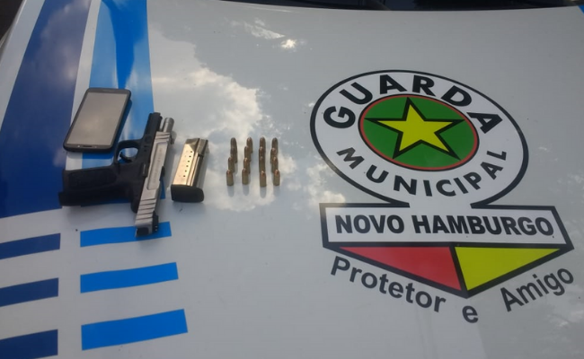 No capô de um veículo com o logo da Guarda Municipal, a arma e as munições
