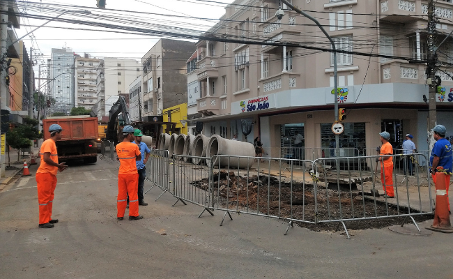 Em uma rua, buraco aberto com trabalhadores no entorno