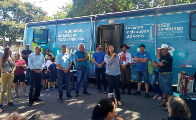 Com um ônibus de fundo, prefeita Fátima ao microfone em pé com pessoas no entorno