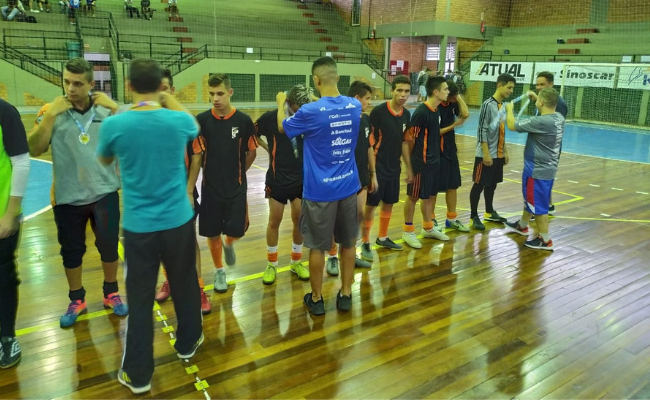 Em uma quadra, meninos perfilados recebem medalhas