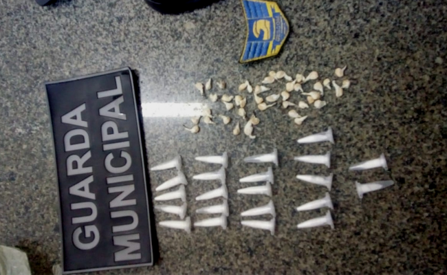 Em cima de uma emsa, 22 pinos de cocaína e 43 pedras de crack com o insígnia da guarda municipal ao lado