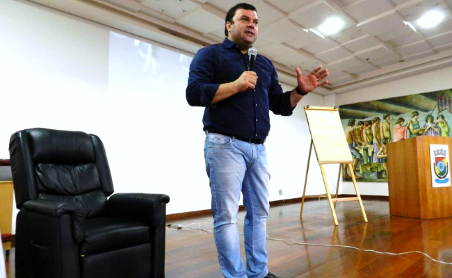 Homem em pé ao microfone em cima de um palco