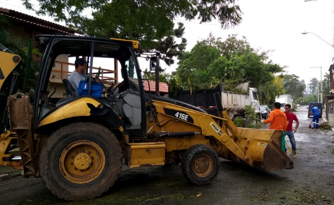Uma retroescavadeira em uma rua carregando galhos