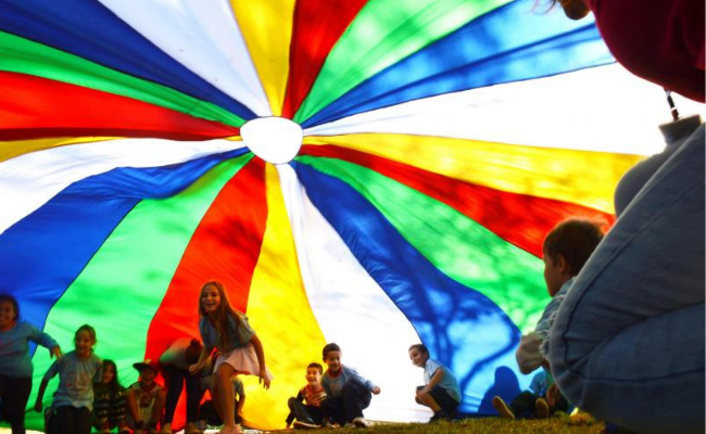 Crianças brincando embaixo de um grande pano colorido