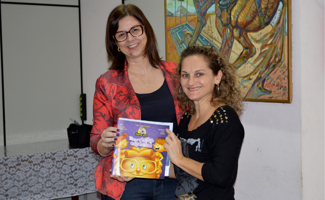 Duas mulheres em pé segurando um livro