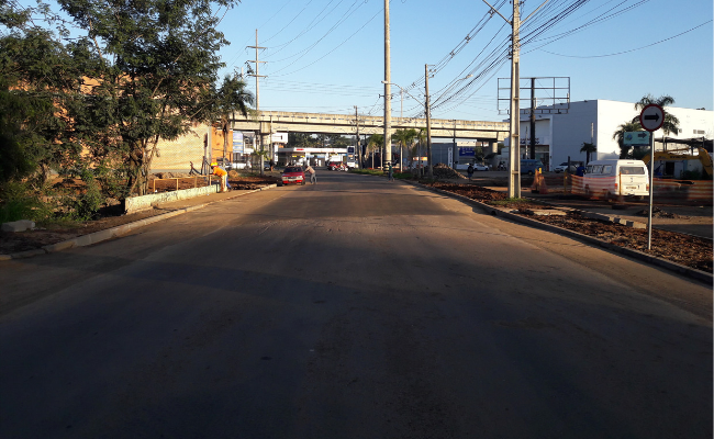 Imagem de uma rua de asfalto com uma ponte ao fundo