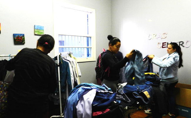 Pessoas escolhendo roupas em cabides numa sala