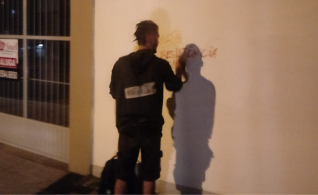 Homem em pé pichando um parede