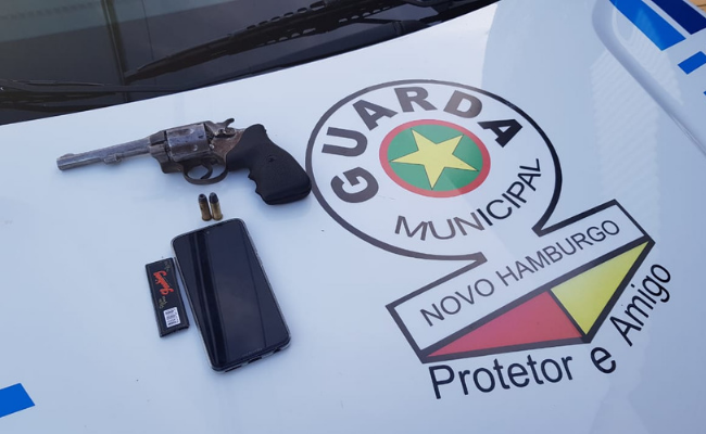 Revólver em cima do capô de um carro da Guarda Municipal