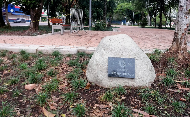 Em uma pedra branca, uma placa colocada no meio desta pedra com o escrito "Reforma 500 anos Reforma Luterana"