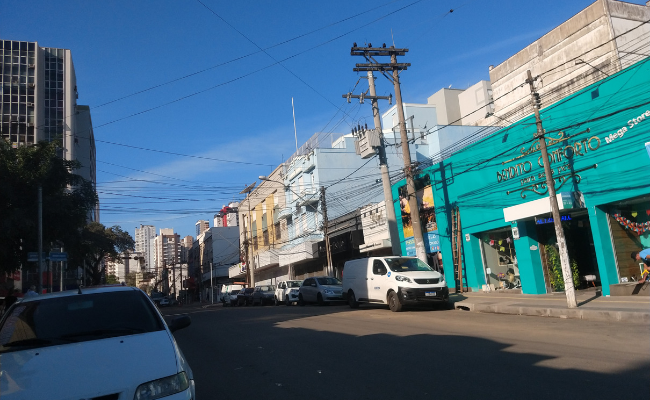 Rua de asfalto com lojas dos dois lados