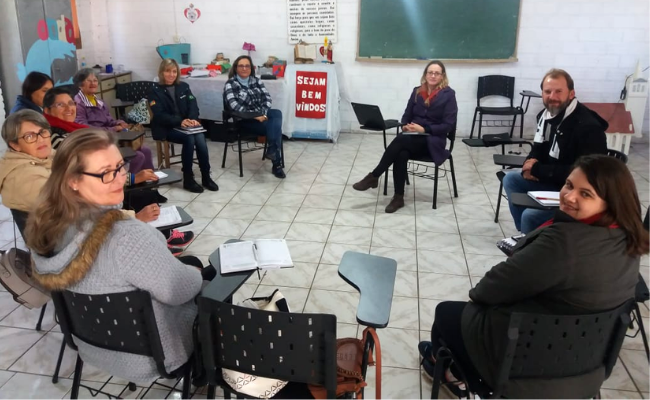 Em uma sala, grupo de pessoas sentadas em círculo