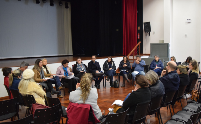 Em uma sala, grupo de pessoas sentadas em círculo