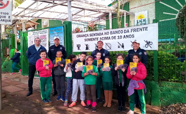 Crianças e três guardas municipais em frente a escola