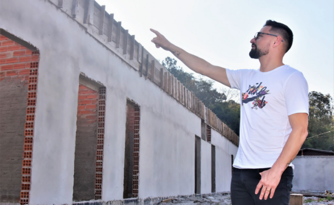 Homem em pé apontando para uma obra
