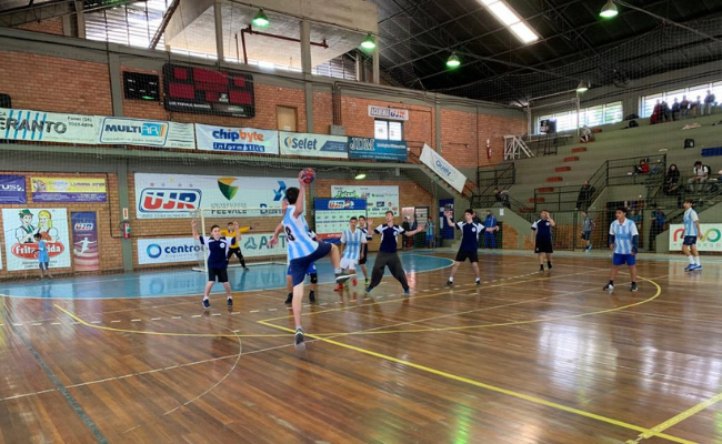Em uma quadra, jovens jogam handebol