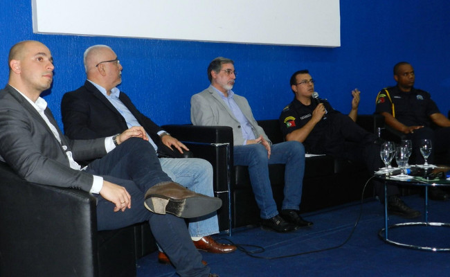 Cinco homens sentados em poltronas em um palco
