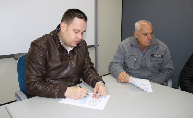 Homem assinando um papel em uma mesa
