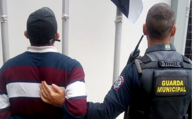 Do lado esquerdo, o preso de costas e à direita o Guarda Municipal também de costas