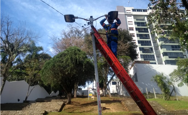 Homem mexendo em um poste de iluminação pública