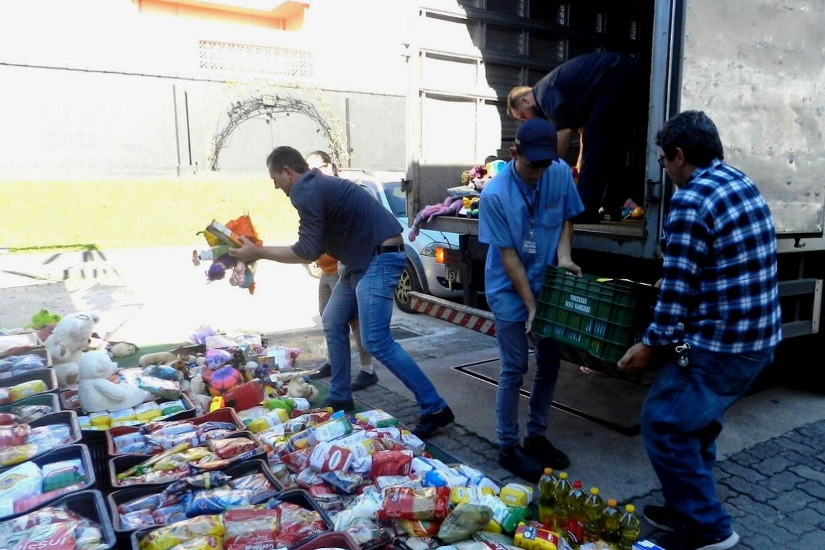 Três homens descarregando alimentos de uma caminhão