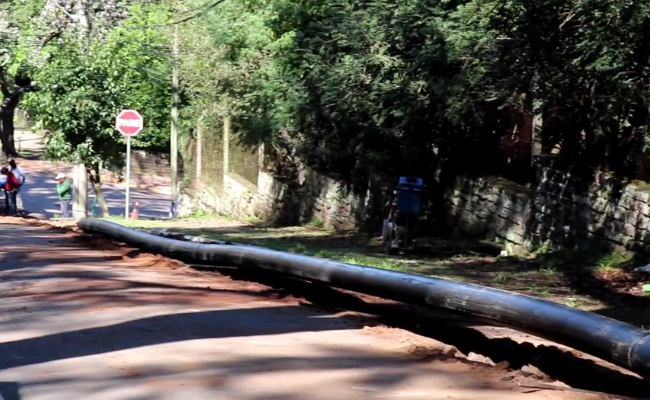 Em uma rua, um cano preto exposto de fora a fora na rua