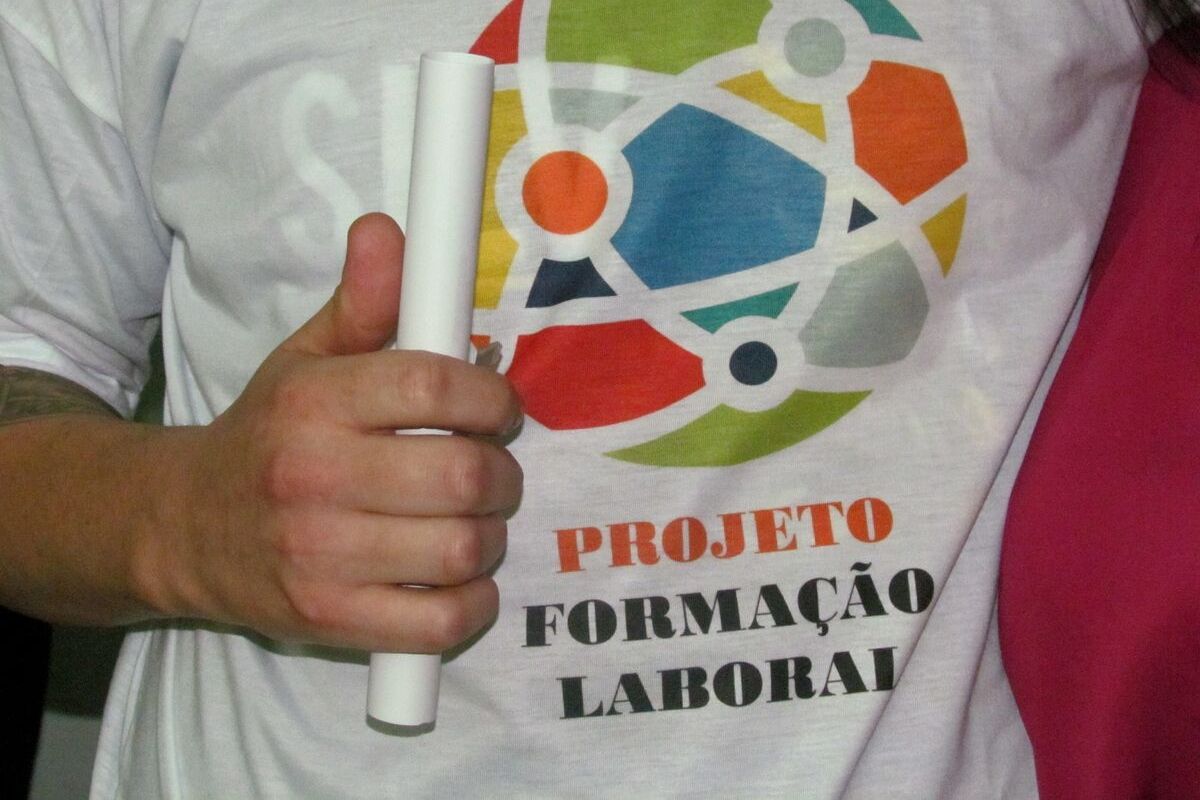 Jovem com a camiseta com o logo do programa segurando uma folha dobrada