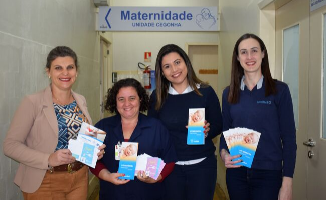 Quatro mulheres em pé segurando um folder no corredor do hospital