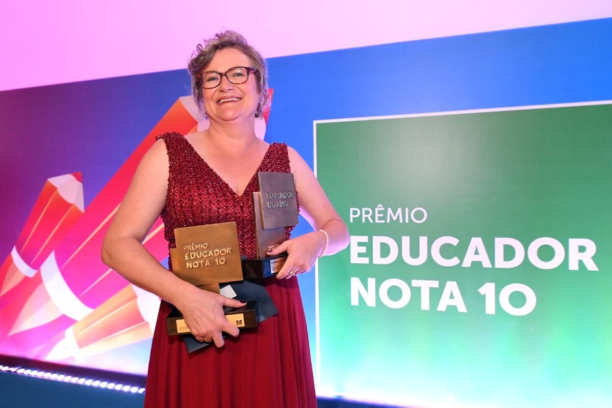 Mulher de vestido vermelho segurando dois troféus