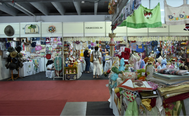 Estandes da Economia Solidária um ao lado do outro em cor branco com os produtos expostos