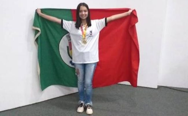 Menina em pé com os braços abertos segurando uma bandeira nas suas costas