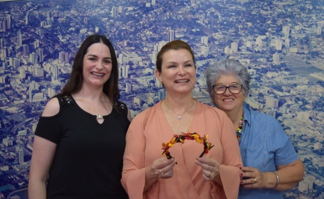 Três mulheres em pé, com a prefeita no meio segurando uma tiara