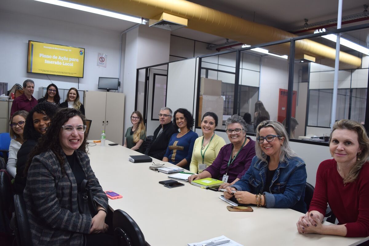 Grupo de pessoas sentadas no entorno de uma grande mesa