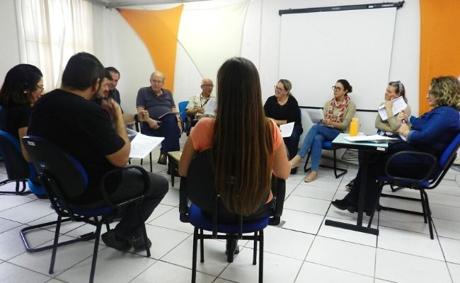 Pessoas sentadas em cadeiras organizadas em círculo
