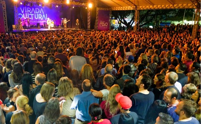 Nando Reis no palco ao fundo e grande público em pé 