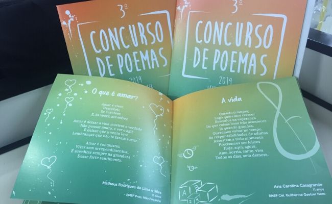 Foto do livro aberto. O livro é verde com letras brancas