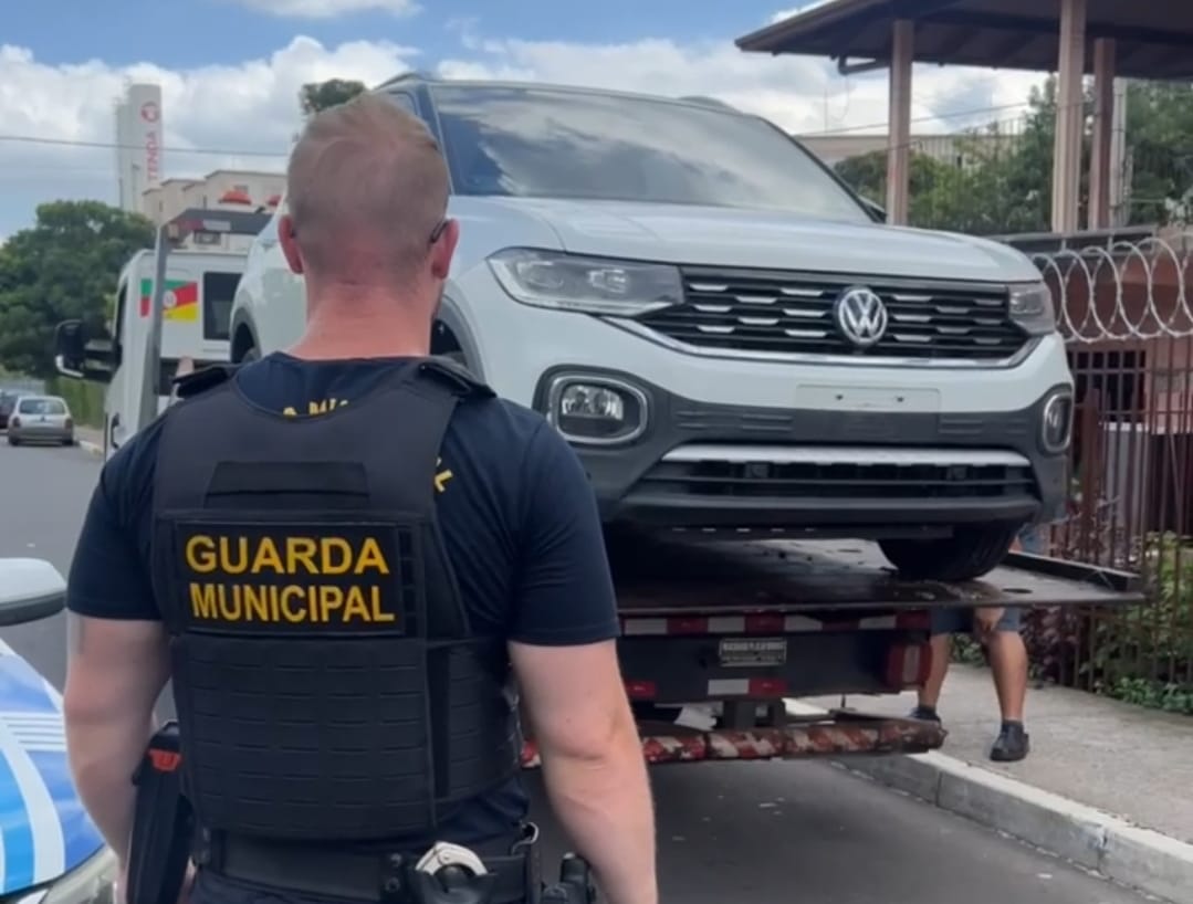 Guarda Municipal em frente a carro roubado com placas adulteradas sendo removido
