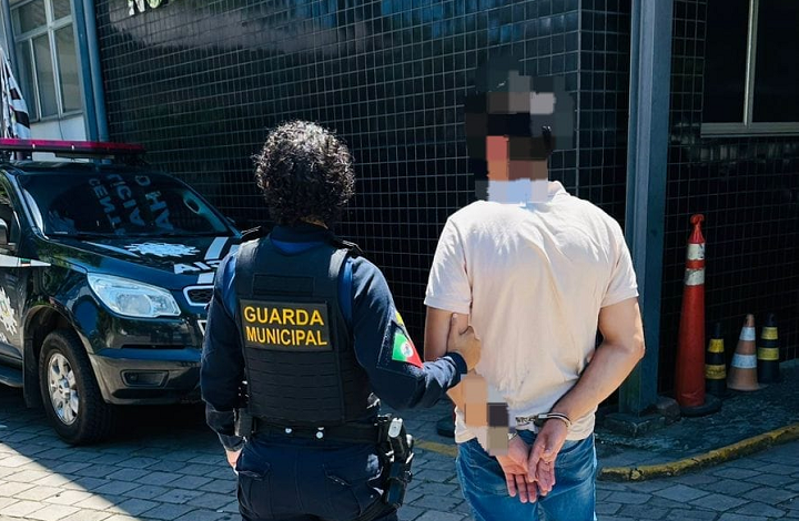 Uma agente da Guarda Municipal conduz foragido algemado atá a delegacia de polícia em Novo Hamburgo