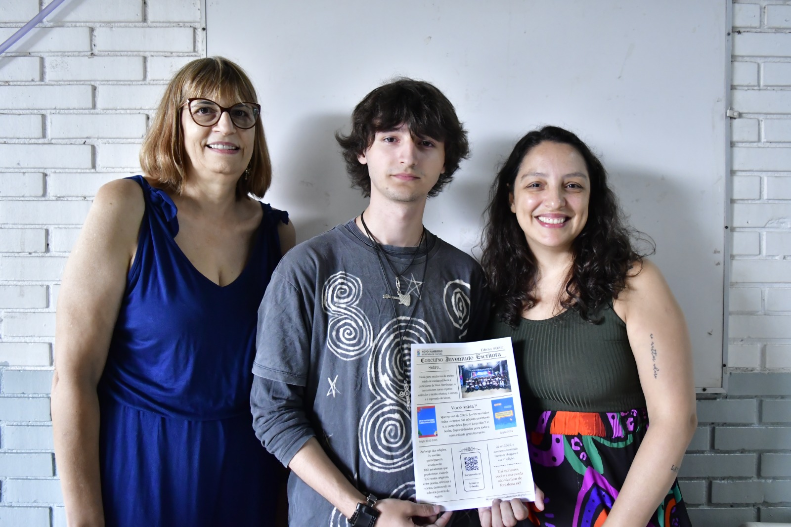 O estudante Vitor, que venceu o concurso em 2024, ao lado da professora de língua portuguesa Evani Dutra (E) e a diretora Caroline Fedre (D)